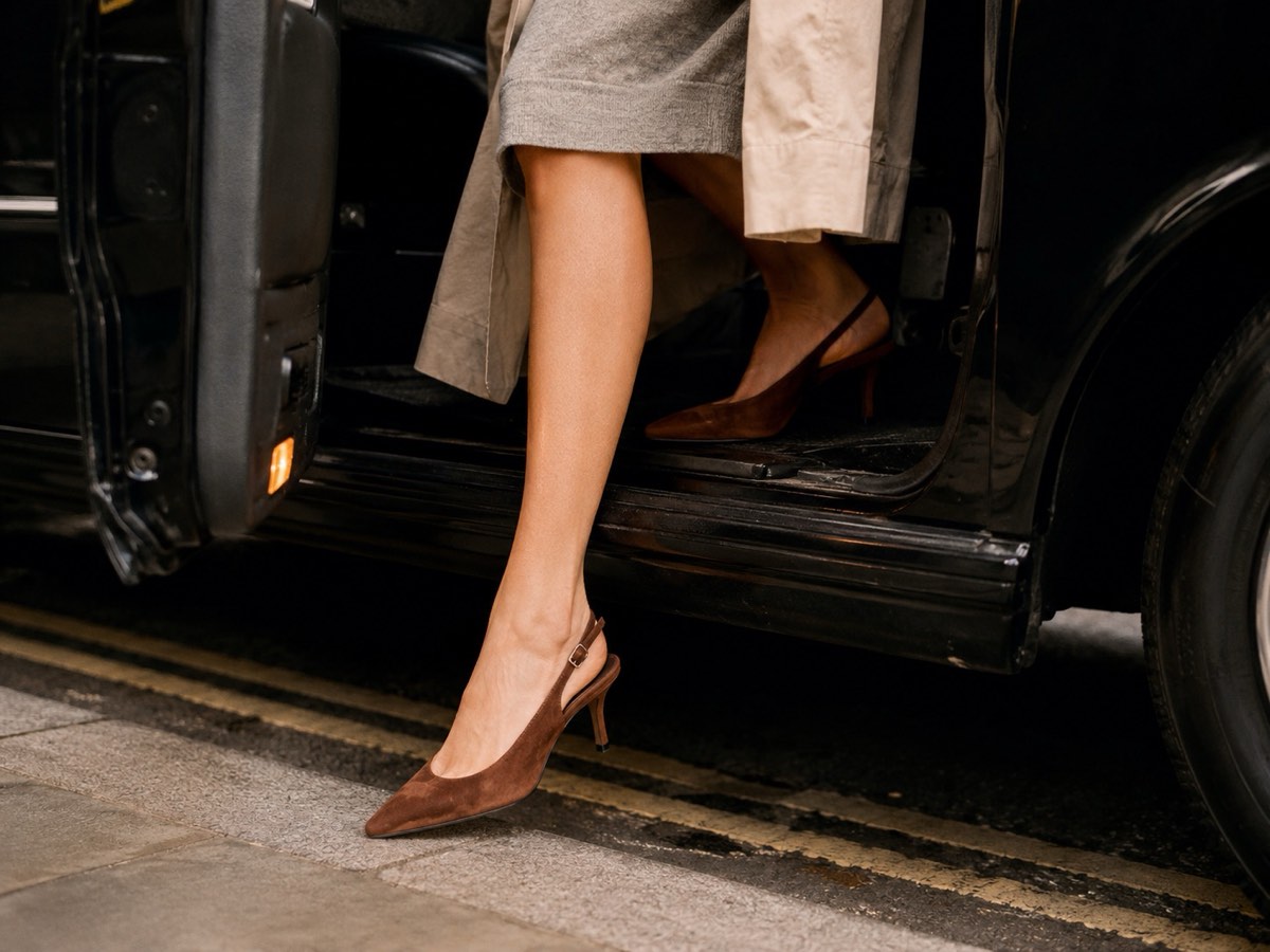 Brown suede slingback kitten heels stepping out of a black cab